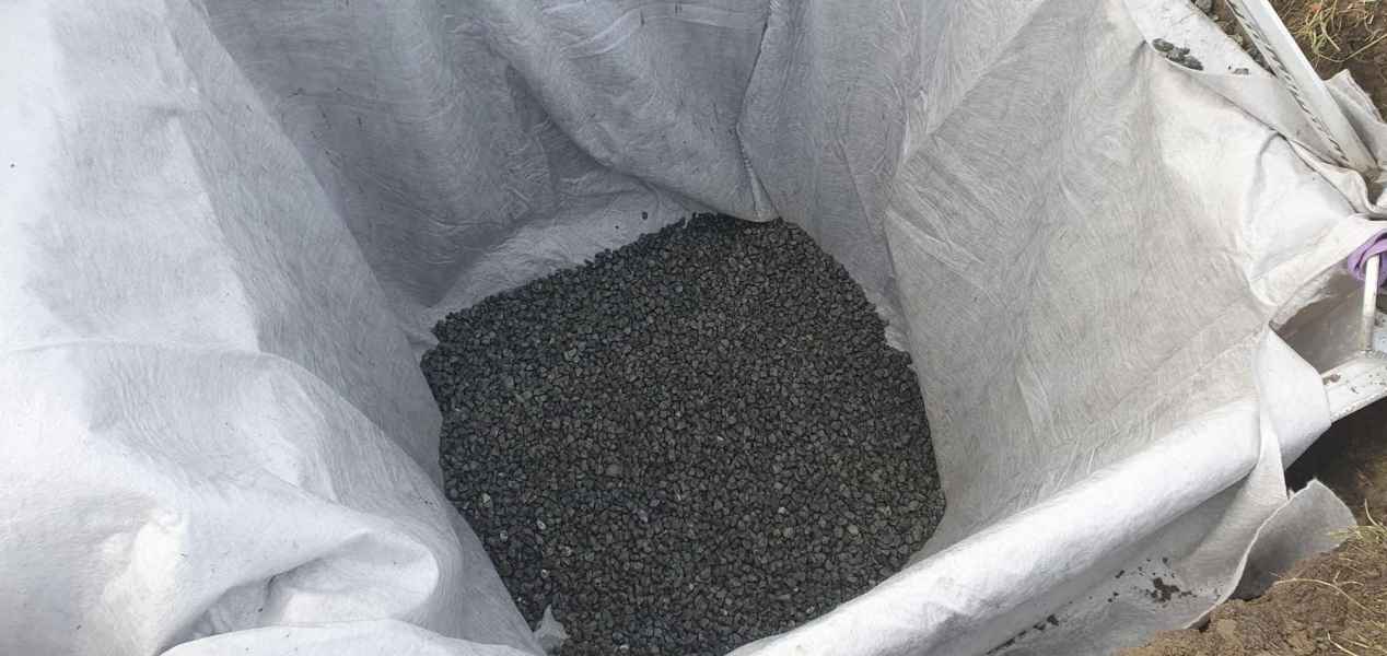 Gravel stones in a white tarpaulin bag, ready for construction or drainage use